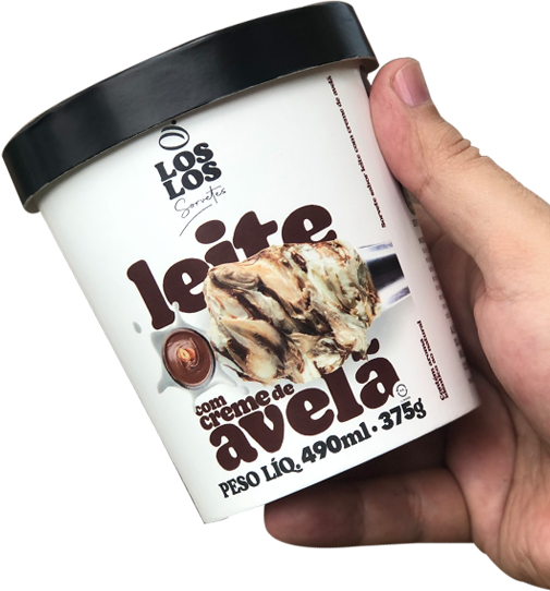 Mão segurando um pote de sorvete no sabor de Leite com Creme de Avelã